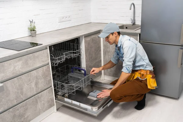 Muž otevírání nebo zavírání myčky nádobí v kuchyni. — Stock fotografie