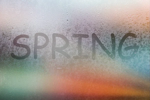 Foggy glass on window with written finger word spring on glass wet orange window in city on sunset — Stock Photo, Image