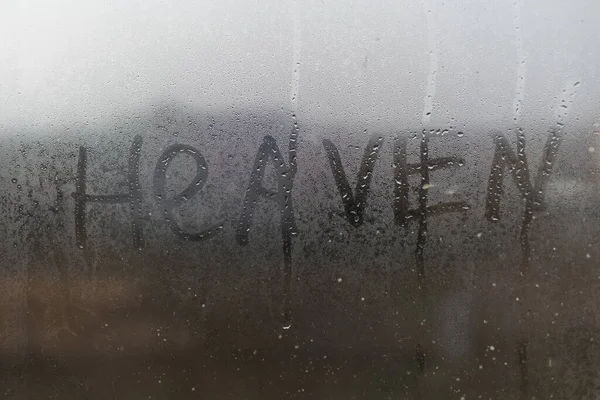 Palabra Cielo, inscripción manuscrita en el cristal. Gotas de agua en el cristal de la ventana —  Fotos de Stock