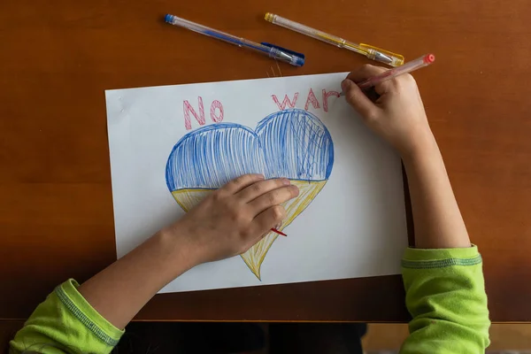 Український прапор і серце жовтого і синього кольору. Дитина малює серце на дошці. — стокове фото