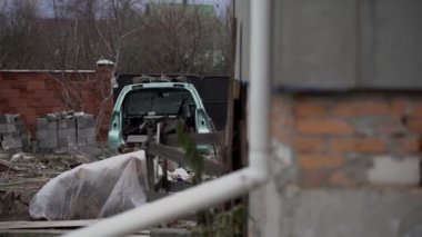 Otoparkta terk edilmiş paslı bir araba. Etrafı çit ve dikenli tellerle çevrili. Otomotiv parçalanması ya da metal işleme için bir kaç araba su birikintisinde duruyor. Eski bir arabanın restorasyonu.