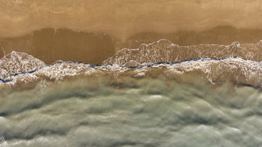 Güzel bir turkuaz denizin kıyısındaki temiz, beyaz kumlu plajın yukarıdan aşağıya manzarası.