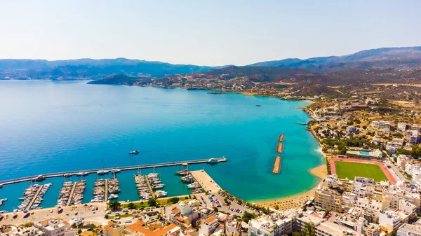 Agios Nikolaos. Kreta. Griekenland. Gebouwen aan de oever van het Voulismeni meer en boten op de pier — Stockfoto