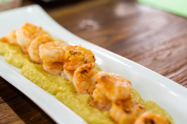 Sarımsaklı karides. Meşhur İspanyol mutfağı. Malzemeler soyulmuş karides, sarımsak ve zeytinyağı. Kil kapta servis edilir. Soğutmadan çabucak yenmeleri gerekir..