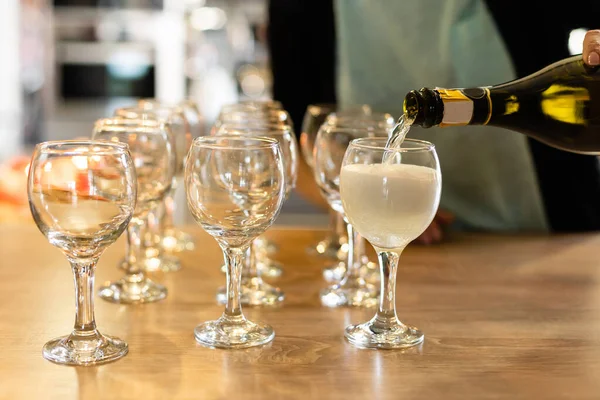 Nalil víno z láhve do sklenici na stůl rozostřeného pozadí — Stock fotografie