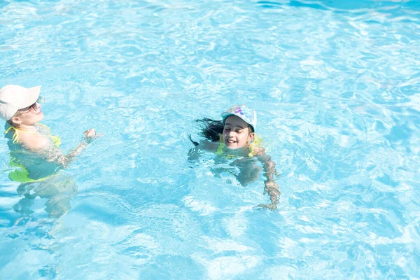 Hermosa mujer con su hija en la piscina — Foto de Stock
