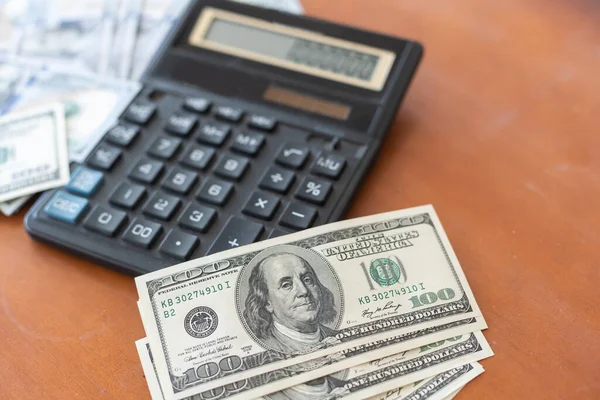 Hesap makinesi ve ahşap masada 100 dolar..