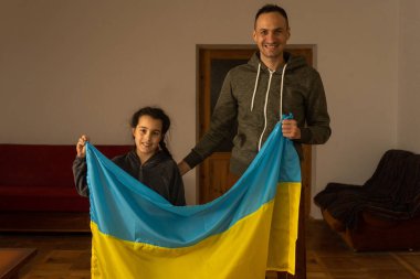bir çocuklu aile kameraya ve Ukrayna bayrağına bakıyor