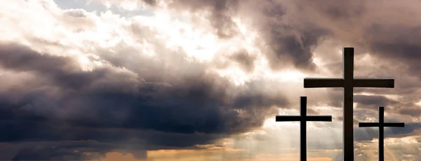 Tři kříže stojí vysoko na svahu pod zataženou oblohou — Stock fotografie