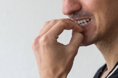 Korkmuş bir adam korkmuş ve arka planda tırnaklarını yiyor..