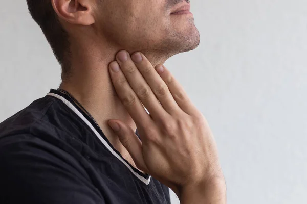 Hombre tocándose el cuello, con irritación de garganta sobre fondo gris —  Fotos de Stock