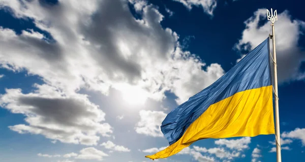 Duża flaga narodowa Ukrainy wznosi się na błękitnym niebie. Wielki żółty sztandar ukraińskiego państwa. Niepodległość, flaga, Dzień Konstytucji, Święto Narodowe, przestrzeń tekstowa. — Zdjęcie stockowe