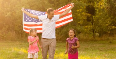 Gün batımında Amerika bayrağıyla mutlu bir aile.