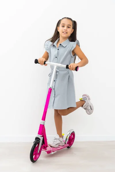 Schattig klein meisje met een scooter. Geïsoleerd op witte achtergrond — Stockfoto