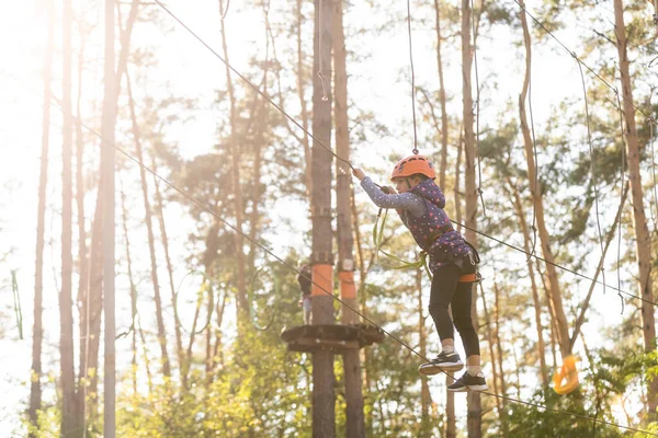 Meisje klimmen in adventure park is een plaats die kan bevatten een grote verscheidenheid van elementen, zoals touwklimmen oefeningen, hindernisbanen en zip-lijnen. — Stockfoto