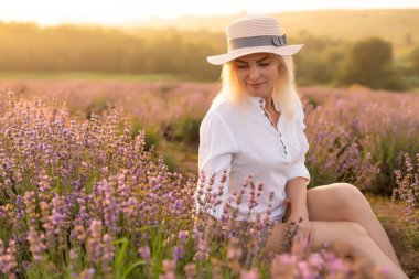 Lavanta tarlasında duran genç bir kadın ve arka planda gün doğumu.