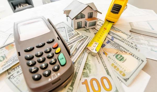 Evin arka planındaki minyatür model, ev planı, para ve hesap makinesi..