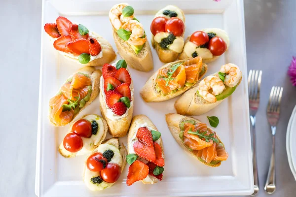 Bruschetta with tomatoes, mozzarella cheese and basil on a cutting board. Traditional italian appetizer or snack, antipasto. Caprese salad bruschetta. Top view with copy space. — Stock Photo, Image