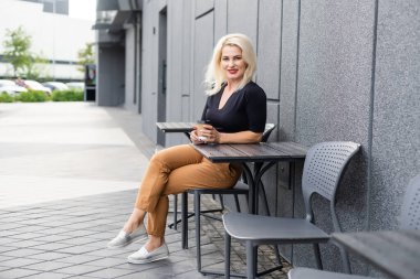 Kafe terasında kahvesini yudumlayan genç bir kadın.