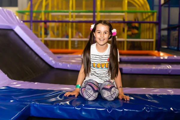 Criança a saltar ao trampolim no parque infantil. Menina criança ativa se divertindo no centro esportivo . — Fotografia de Stock