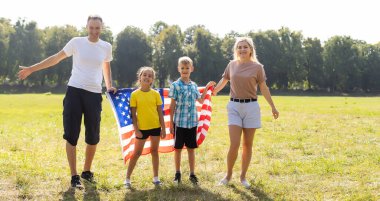 Tarlada Amerikan bayrağı taşıyan güzel bir aile. Bağımsızlık Günü, 4 Temmuz.