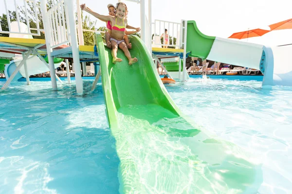 Dos chicas chapotean en una piscina al aire libre en verano. Niños felices, hermana jugando, disfrutando del tiempo soleado en la piscina pública —  Fotos de Stock