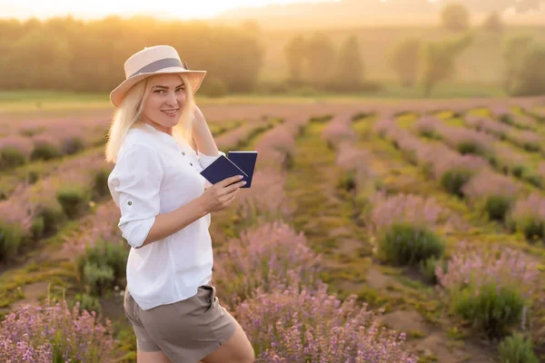 Egy boldog, mosolygós nő portréja, aki útlevelet tart a levendulamezőn. — Stock Fotó