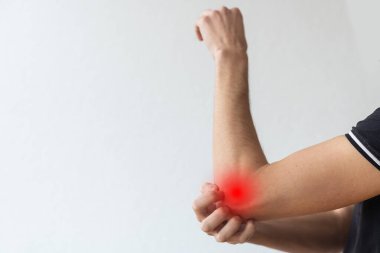 Deri iltihabı, egzama, alerji, sedef hastalığı. Kolunu kaşıyan bir adam, gri stüdyo arka planı. Adam kaşınıyor dirseğinde, kopyala boşluğu