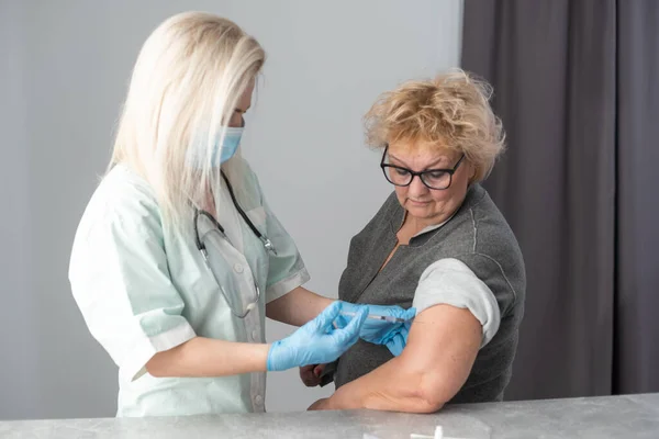 Врач общей практики вакцинирует старого пациента в клинике с копировальным пространством. Доктор делает укол пожилой женщине в больнице. Медсестра держит шприц перед тем, как сделать Ковид-19 или коронавирусную вакцину. — стоковое фото