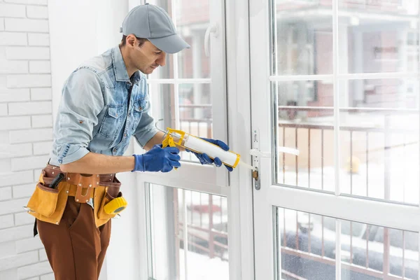 Byggnadsarbetare sätta tätning skumtejp på fönster i hus — Stockfoto