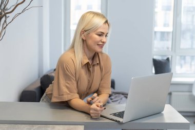 Güzel sarışın bayan dizüstü bilgisayarda çalışıyor. Evdeki koltuğa otur ve pazartesi günü için benzin dükkanlarını kontrol et. Alternatif ofis için teknoloji kadını konsepti.
