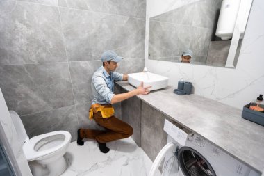 Bir adam banyoda kabine üzerinde lavabo ayarlama
