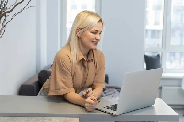 Pěkná krásná blondýnka pracuje u notebooku, sedne si doma na pohovku - zkontrolujte si, zda v obchodě s olinem pro prodej v kybernetickém pondělí - technologie žena koncept pro alternativní kancelář na volné noze — Stock fotografie