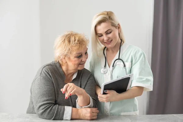 Egészségügyi látogató és egy idős nő otthoni látogatás során. — Stock Fotó
