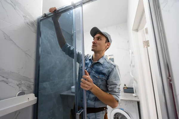 Repairmen in uniform measuring modern shower cabin in bathroom. — Stock Photo, Image