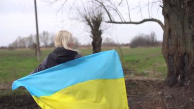 Ukrayna bayrağı yanmış ağacın yanında.