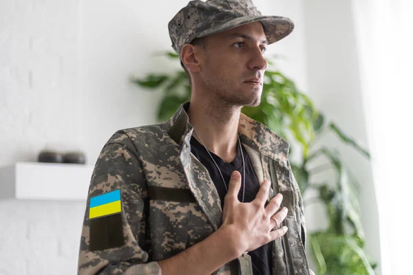 Guerreiro homem ucraniano vestido com um uniforme militar pixel a bandeira amarelo-azul da Ucrânia — Fotografia de Stock