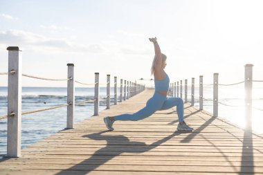 denizin kenarında yoga egzersizleri yapıyor kadın.