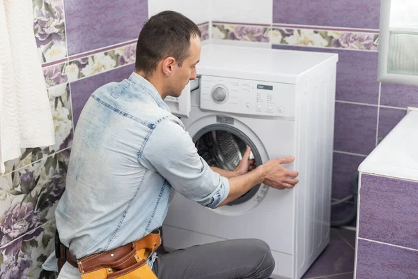 Çalışan tesisatçı çamaşırhanedeki çamaşır makinesini tamir ediyor. — Stok fotoğraf