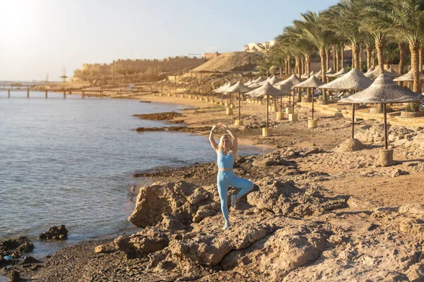 Atractiva mujer en forma practicando embestidas laterales, haciendo ejercicio en la playa en un día soleado brillante. Estilo de vida saludable, entrenamiento al aire libre — Foto de Stock
