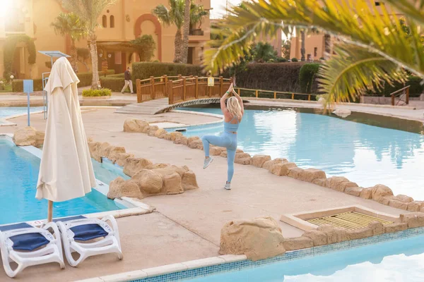 Hermosa mujer joven en forma haciendo ejercicio al aire libre junto a la piscina — Foto de Stock