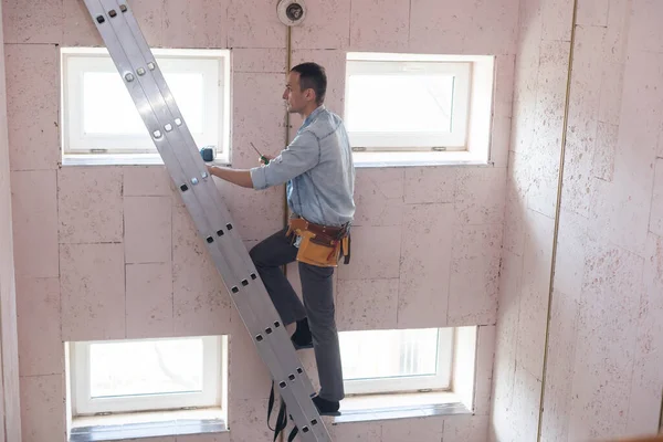 Hombre de pie en la escalera cambiando una bombilla. — Foto de Stock