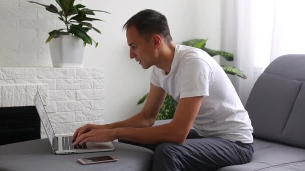 लॅपटॉप बसलेला आकर्षक तरुण माणूस — स्टॉक व्हिडिओ