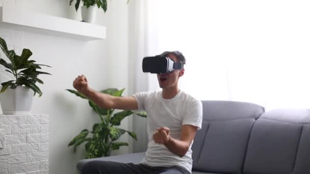 Joven hombre guapo utiliza gafas de realidad virtual y conduce un coche en casa, en la sala de estar - primer plano — Vídeos de Stock