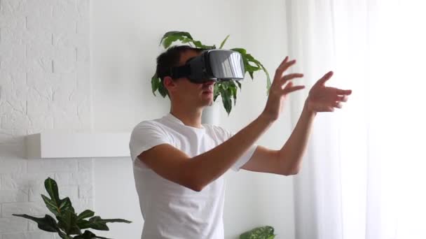 Mand iført VR headset i stuen. Brug fagter med hænder. Flot mand i hvile brug VR briller. Nye teknologier. Tryk på noget ved hjælp af moderne virtual reality briller. – Stock-video
