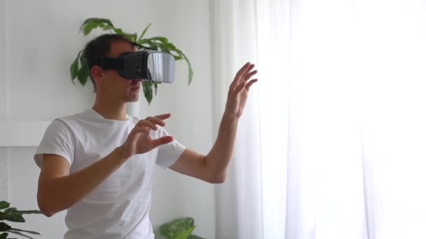 Mand iført VR headset i stuen. Brug af gestus med hænder – Stock-video