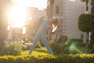 Havalandırma egzersizleri yapan formda bir atlet kadın tropikal bahçe yüzme havuzu, sabah erkenden otel tatili, sağlık hizmetleri, refah...