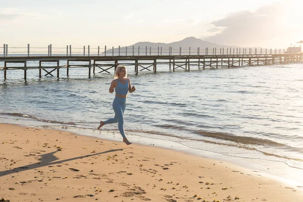 Donna che corre sulla spiaggia al mattino sunrise fitness workout sport — Foto Stock