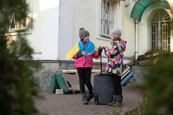 Ukrajna katonai migráció. Két kislány egy bőrönddel. Ukrajna zászlója, segíts! Válság, katonai konfliktus — Stock Fotó