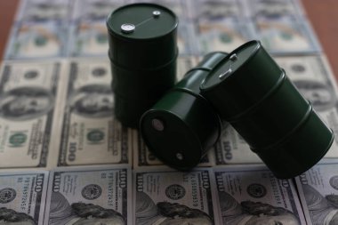 beyaz zemin üzerinde bir varil ve dolar faturaları.